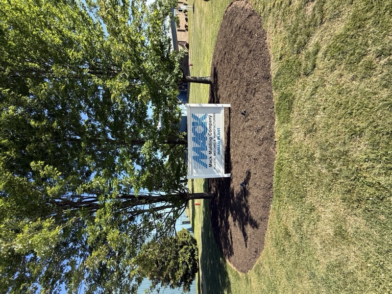 AS Landscape crew finishing a freshly mown lawn with the company sign in the yard
